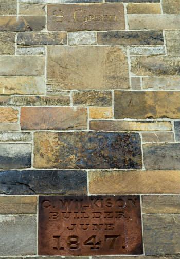 Brown stone builder wall plaque dated June 1847 surrounded by brown, grey, gold and black stone